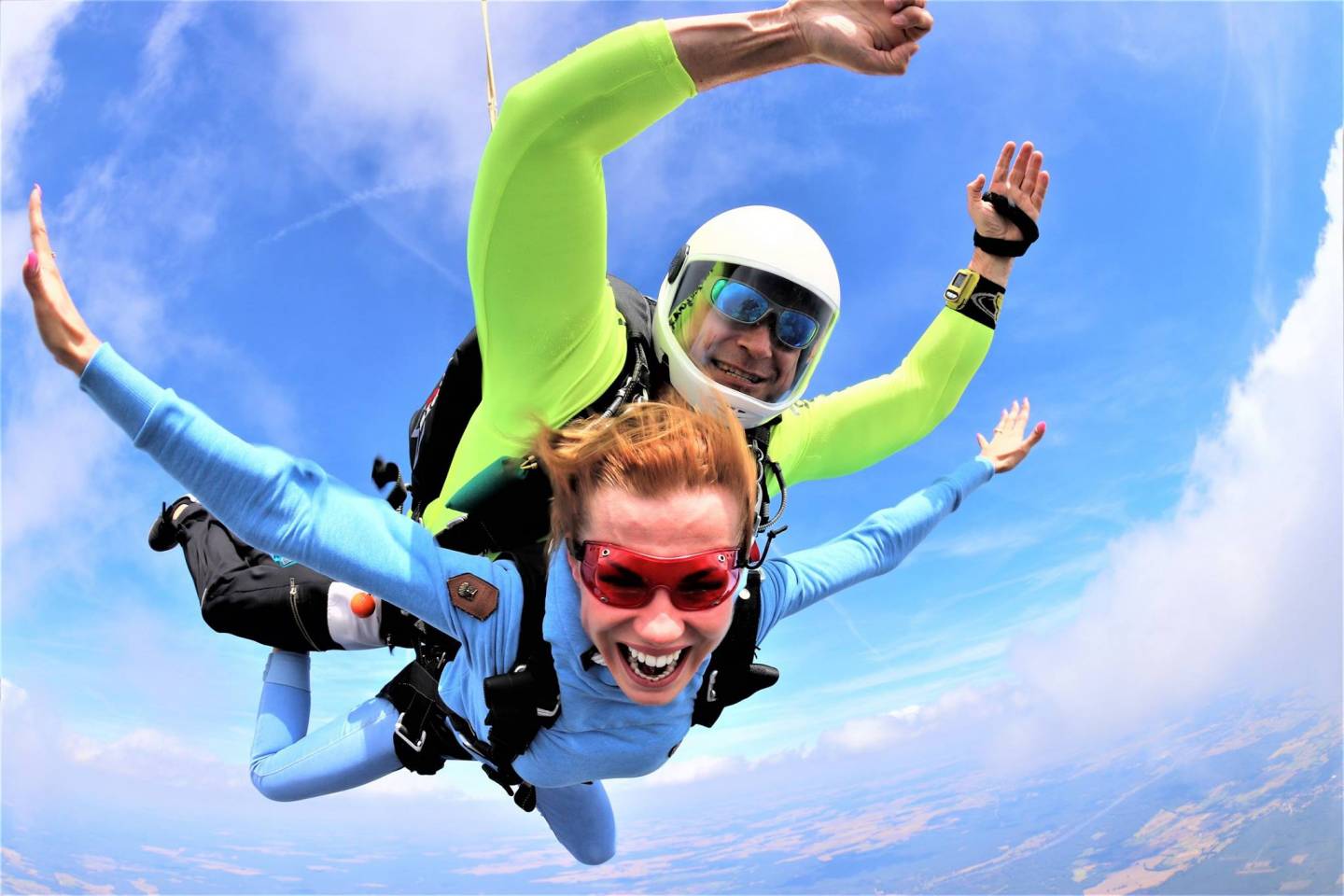 Dwie osoby skaczą ze spadochronem w tandemie.