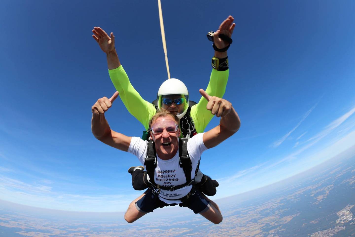 Dwóch radosnych mężczyzn skacze ze spadochronem.