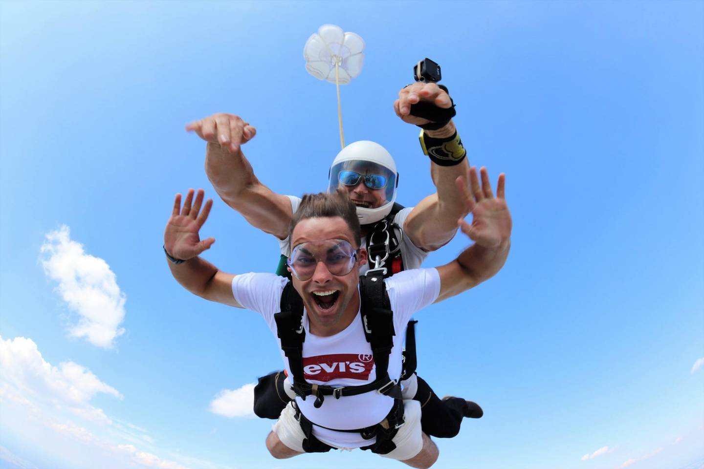 Dwóch mężczyzn skaczących ze spadochronem w tandemie w letni dzień.